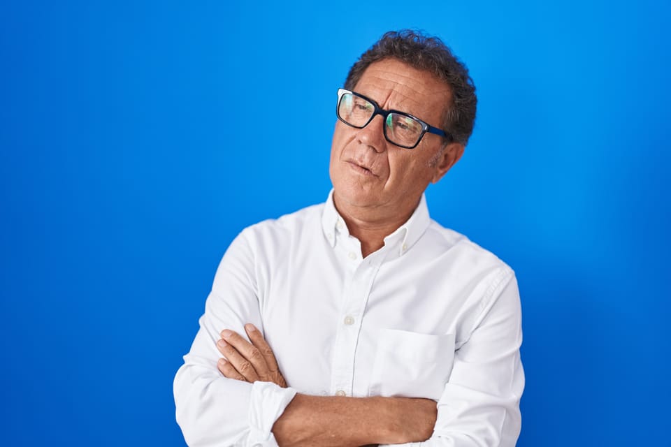 Picture of an older man with his arms crossed looking over to the side, indicating he is thinking about something.