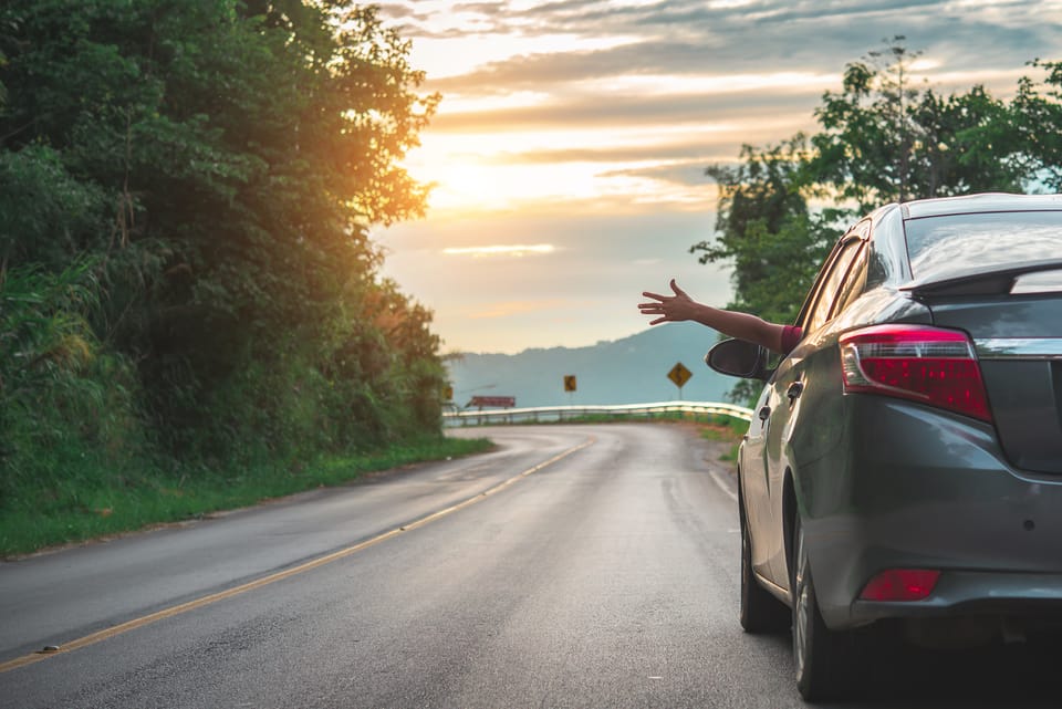 Image of someone driving a car with their hand out the window feeling the wind, living spontaneously.